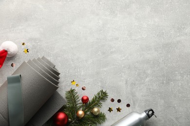 Photo of Flat lay composition with yoga mat and Christmas decor on gray textured background, space for text