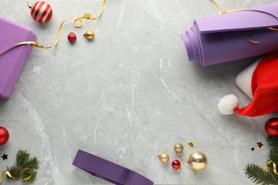 Photo of Flat lay composition with yoga mat and Christmas decor on gray textured background, space for text