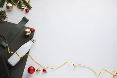 Photo of Flat lay composition with yoga mat and Christmas decor on white background, space for text