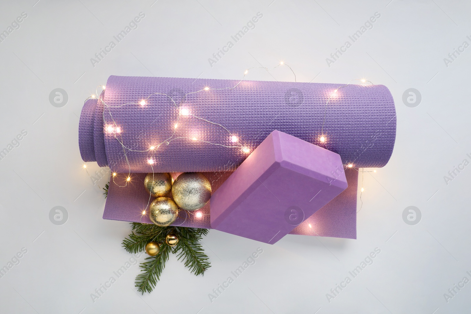 Photo of Yoga mat, block and Christmas decor on white background, top view