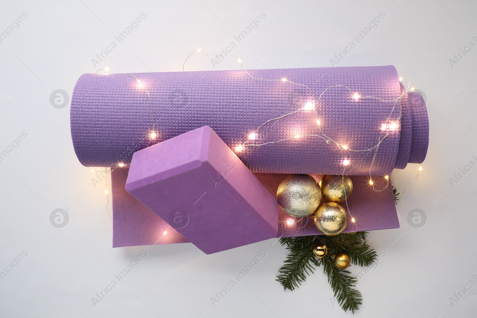 Photo of Yoga mat, block and Christmas decor on white background, top view