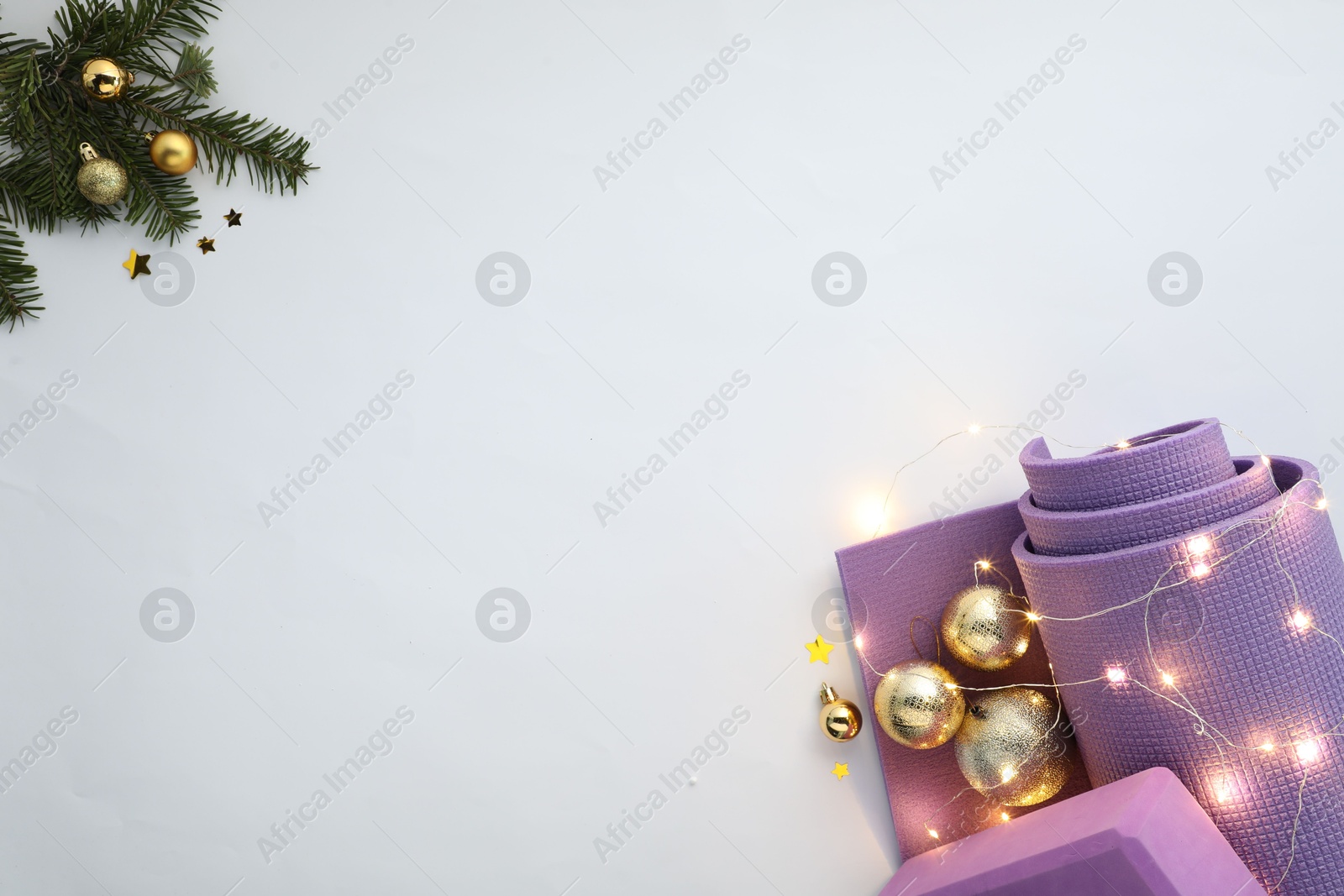 Photo of Yoga mat, block and Christmas decor on white background, flat lay. Space for text