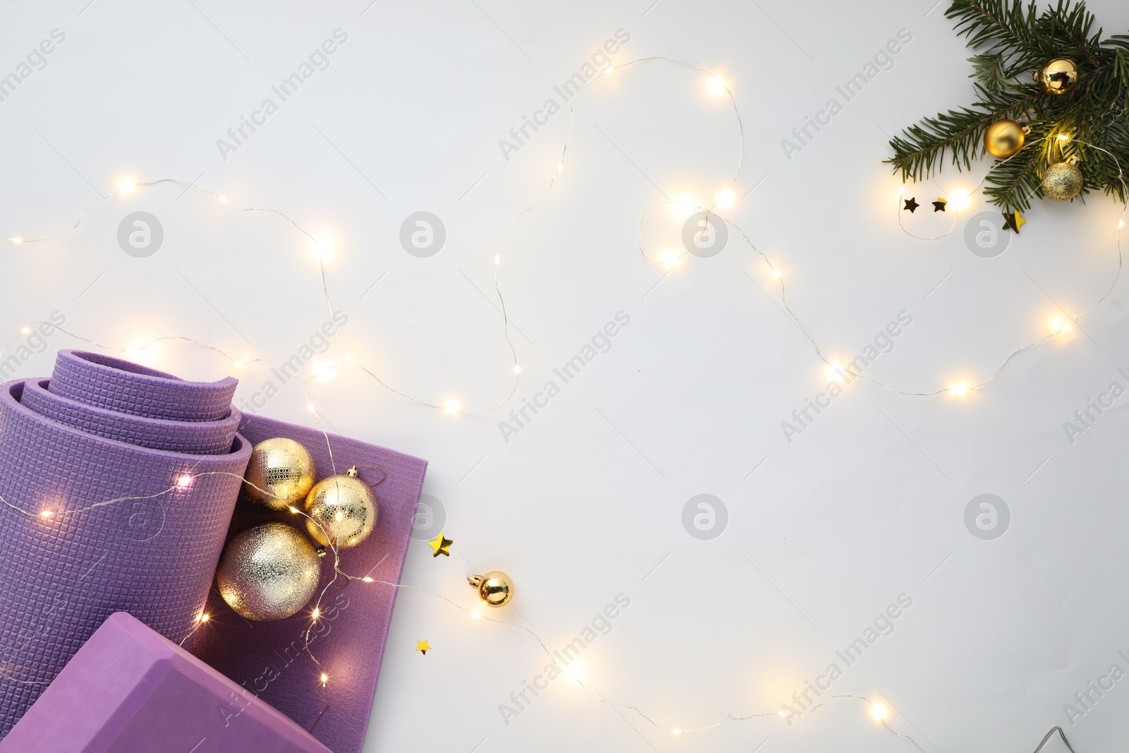 Photo of Yoga mat, block and Christmas decor on white background, flat lay. Space for text