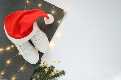 Photo of Yoga mat, sneakers, Santa hat and Christmas decor on white background, top view. Space for text