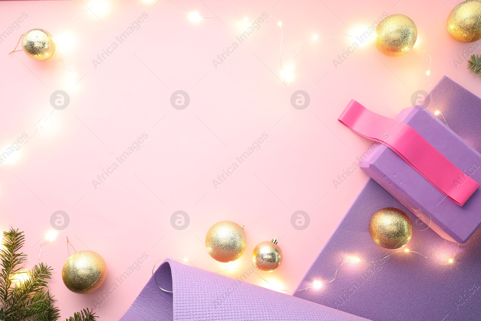 Photo of Yoga mat, fitness equipment and Christmas decor on pink background, flat lay. Space for text