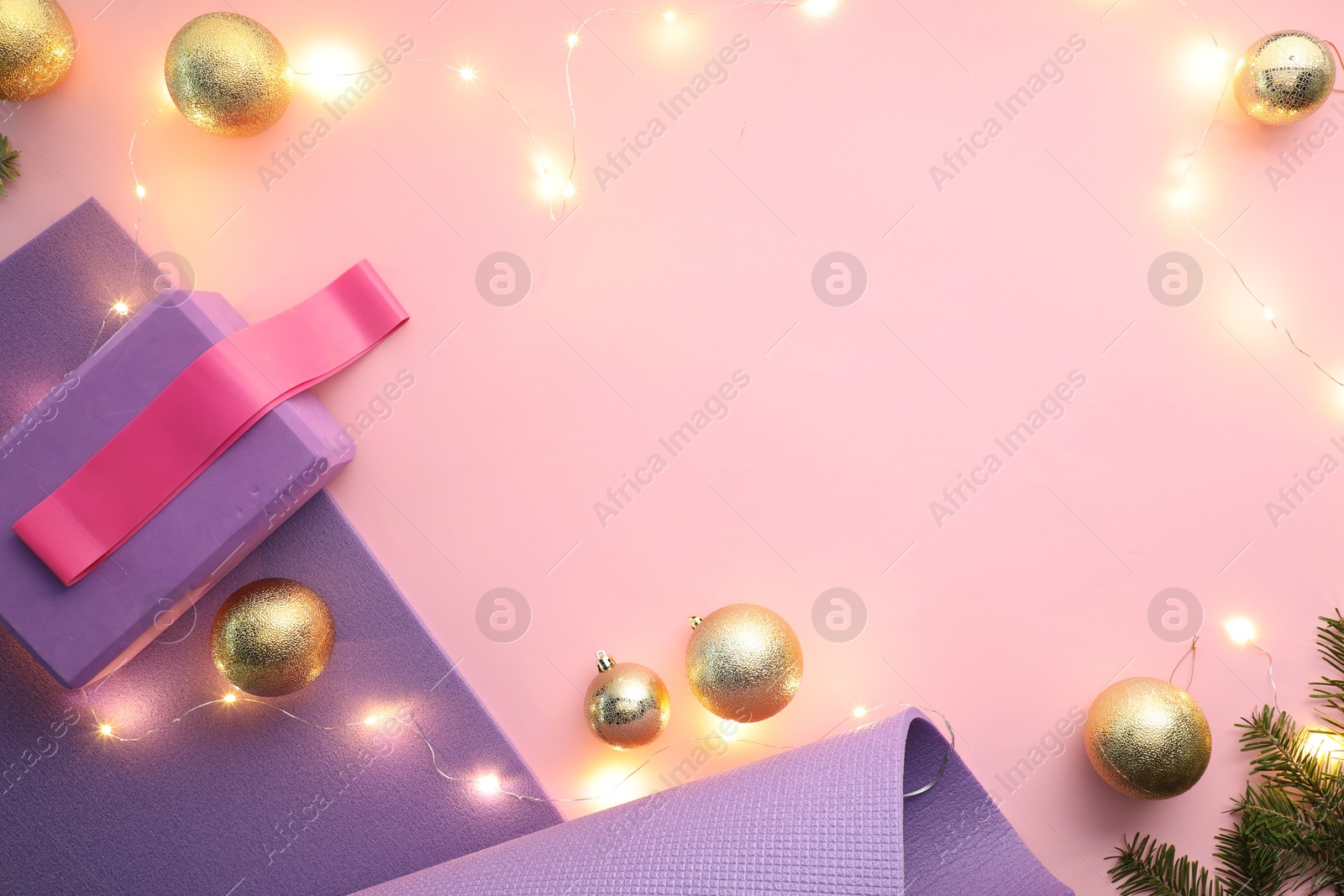 Photo of Yoga mat, fitness equipment and Christmas decor on pink background, flat lay. Space for text