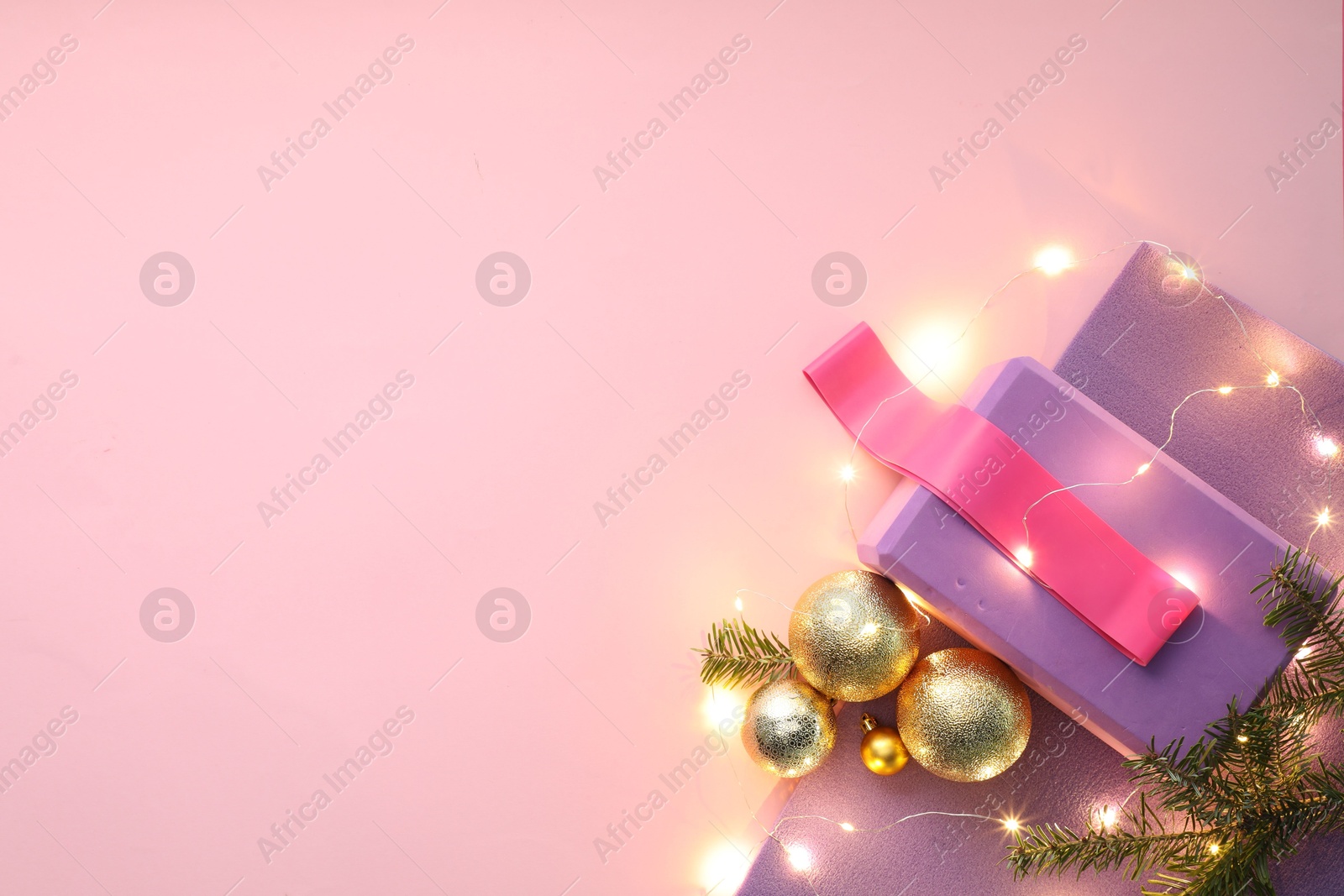 Photo of Yoga mat, fitness equipment and Christmas decor on pink background, flat lay. Space for text