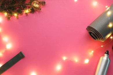 Photo of Yoga mat, band, bottle and Christmas decor on pink background, flat lay. Space for text