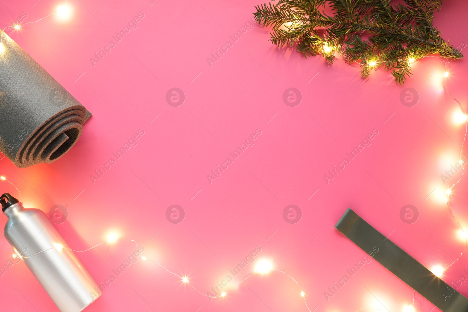 Photo of Yoga mat, band, bottle and Christmas decor on pink background, flat lay. Space for text