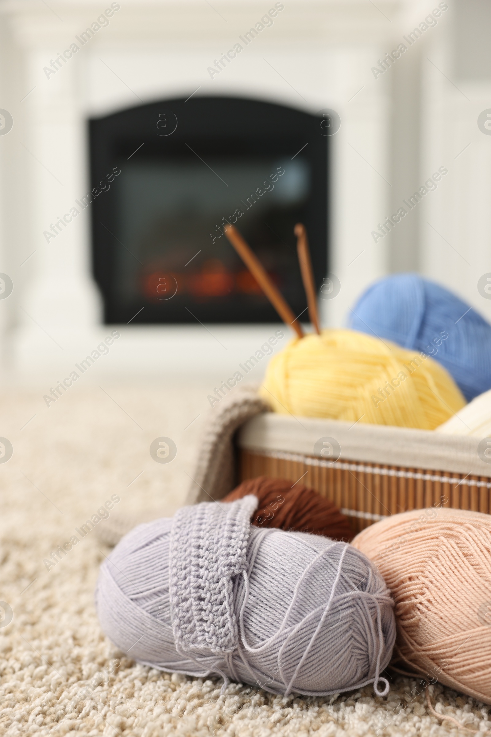 Photo of Colorful yarns, crochet sample, hooks and basket on soft carpet indoors, closeup. Space for text