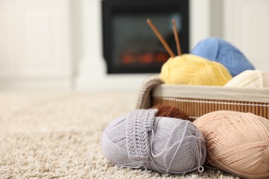 Colorful yarns, crochet sample, hooks and basket on soft carpet indoors, closeup. Space for text