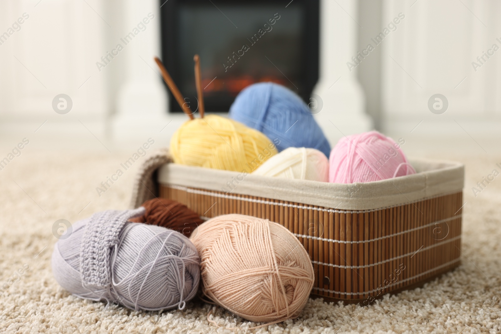 Photo of Colorful yarns, crochet sample, hooks and basket on soft carpet indoors, closeup