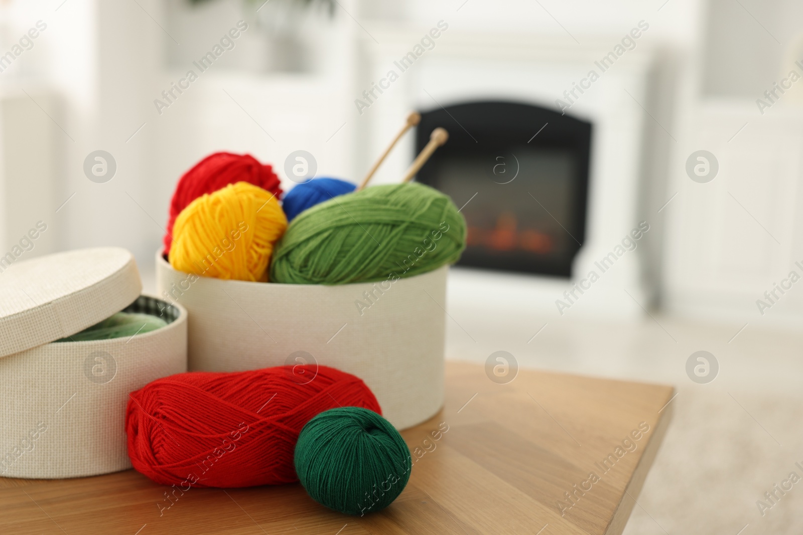 Photo of Boxes with colorful yarns and knitting needles on wooden table indoors. Space for text