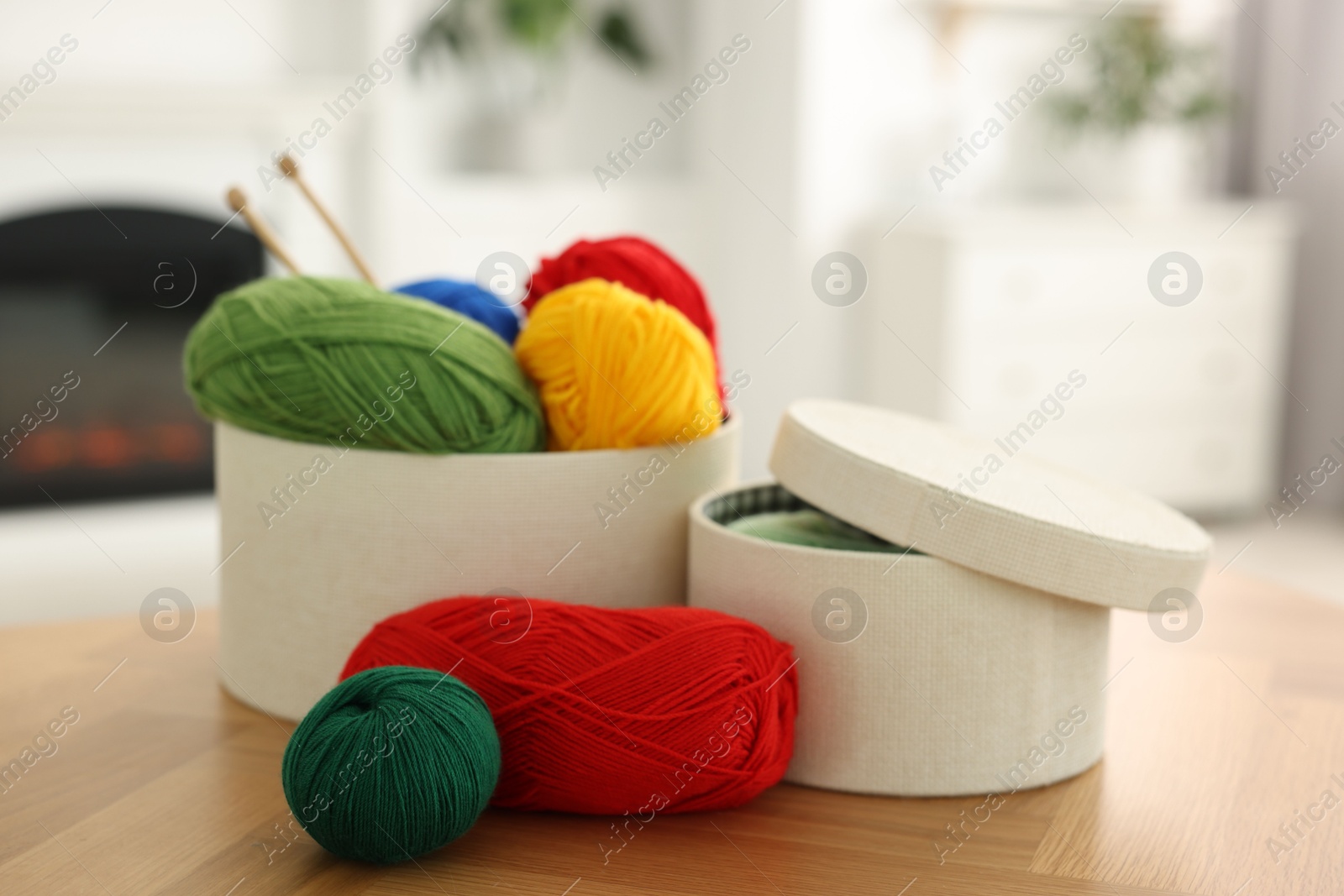 Photo of Boxes with colorful yarns and knitting needles on wooden table indoors