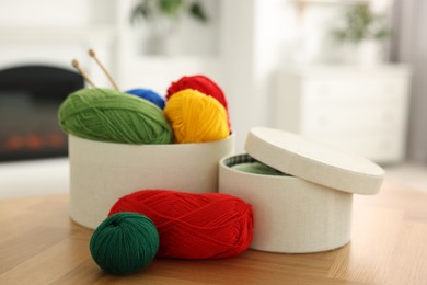 Boxes with colorful yarns and knitting needles on wooden table indoors