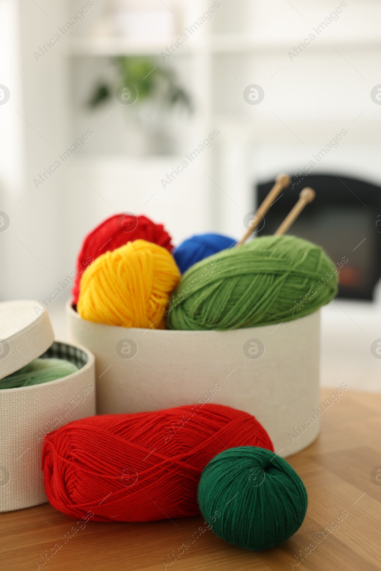 Photo of Boxes with colorful yarns and knitting needles on wooden table indoors