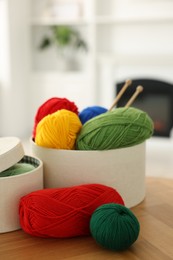 Photo of Boxes with colorful yarns and knitting needles on wooden table indoors