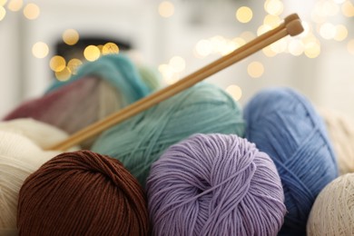 Photo of Many colorful yarns and knitting needles against blurred lights, closeup