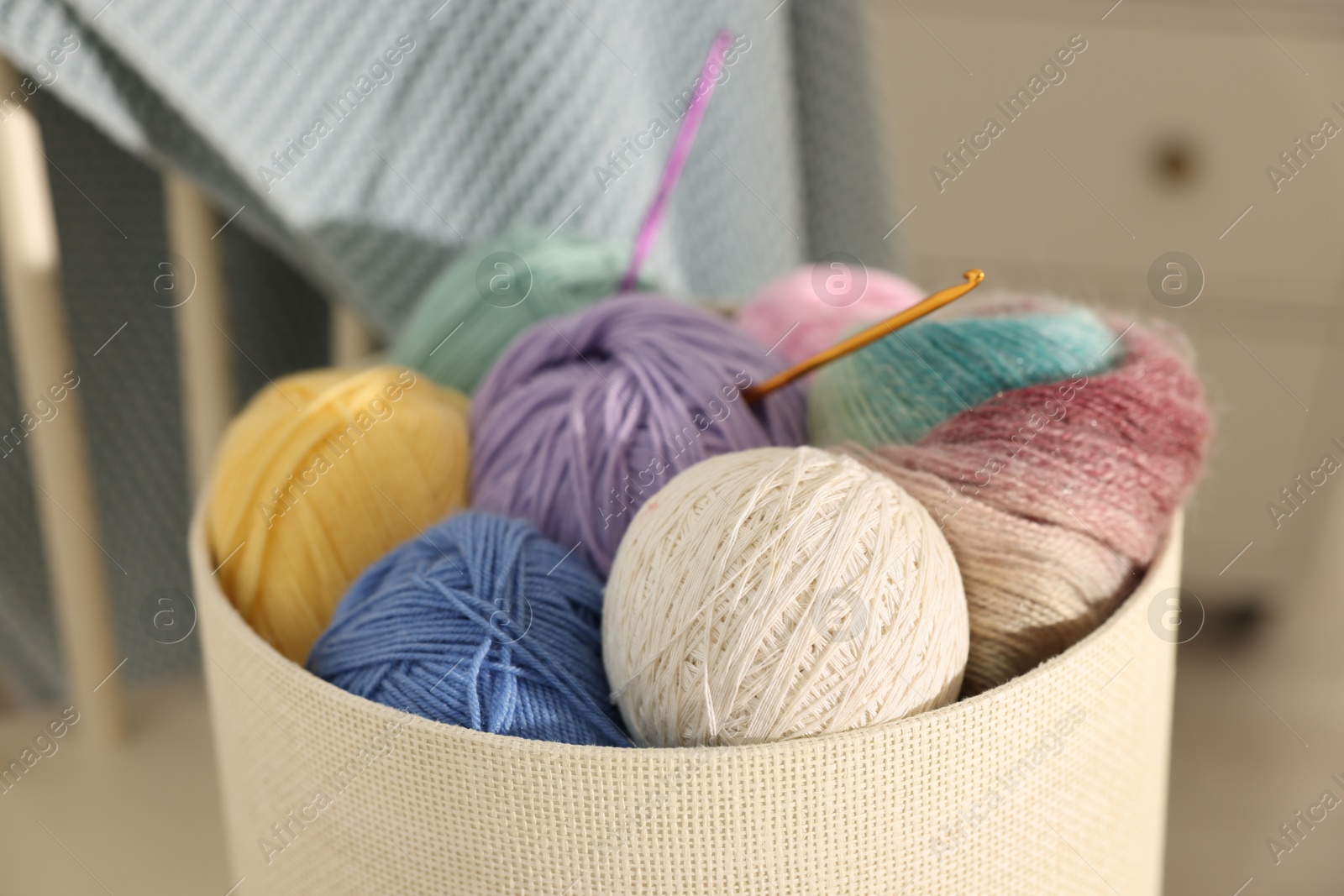 Photo of Many colorful yarns and crochet hooks in box on blurred background, closeup