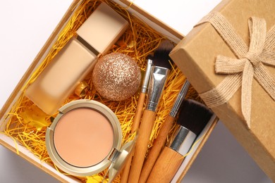 Photo of Makeup brushes, decorative cosmetics and Christmas decor in box on white background, top view