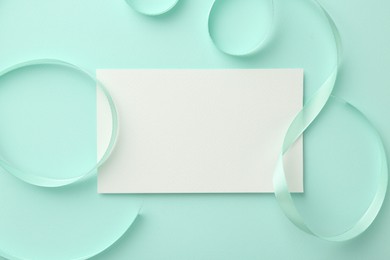 Photo of Blank card and ribbons on turquoise background, top view