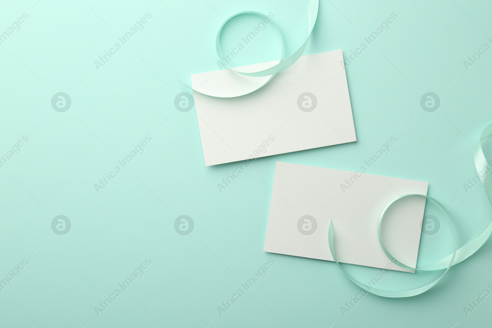 Photo of Blank cards and ribbons on turquoise background, flat lay. Space for text