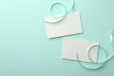 Blank cards and ribbons on turquoise background, flat lay. Space for text