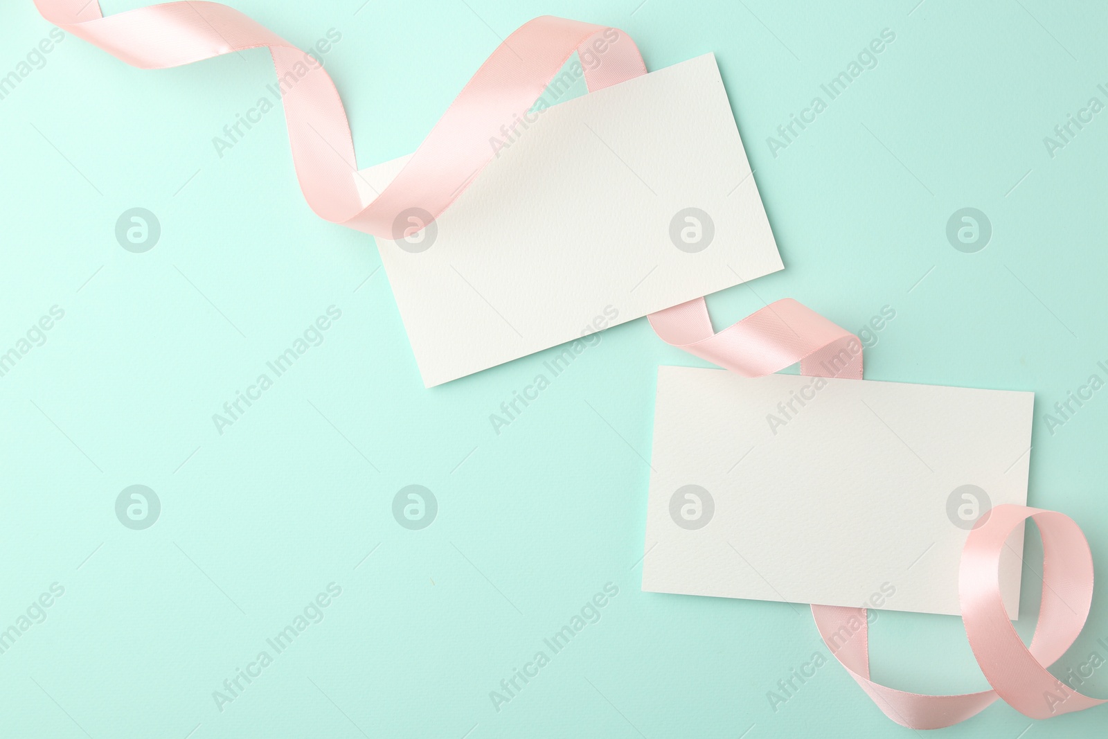 Photo of Blank cards and ribbons on turquoise background, flat lay. Space for text