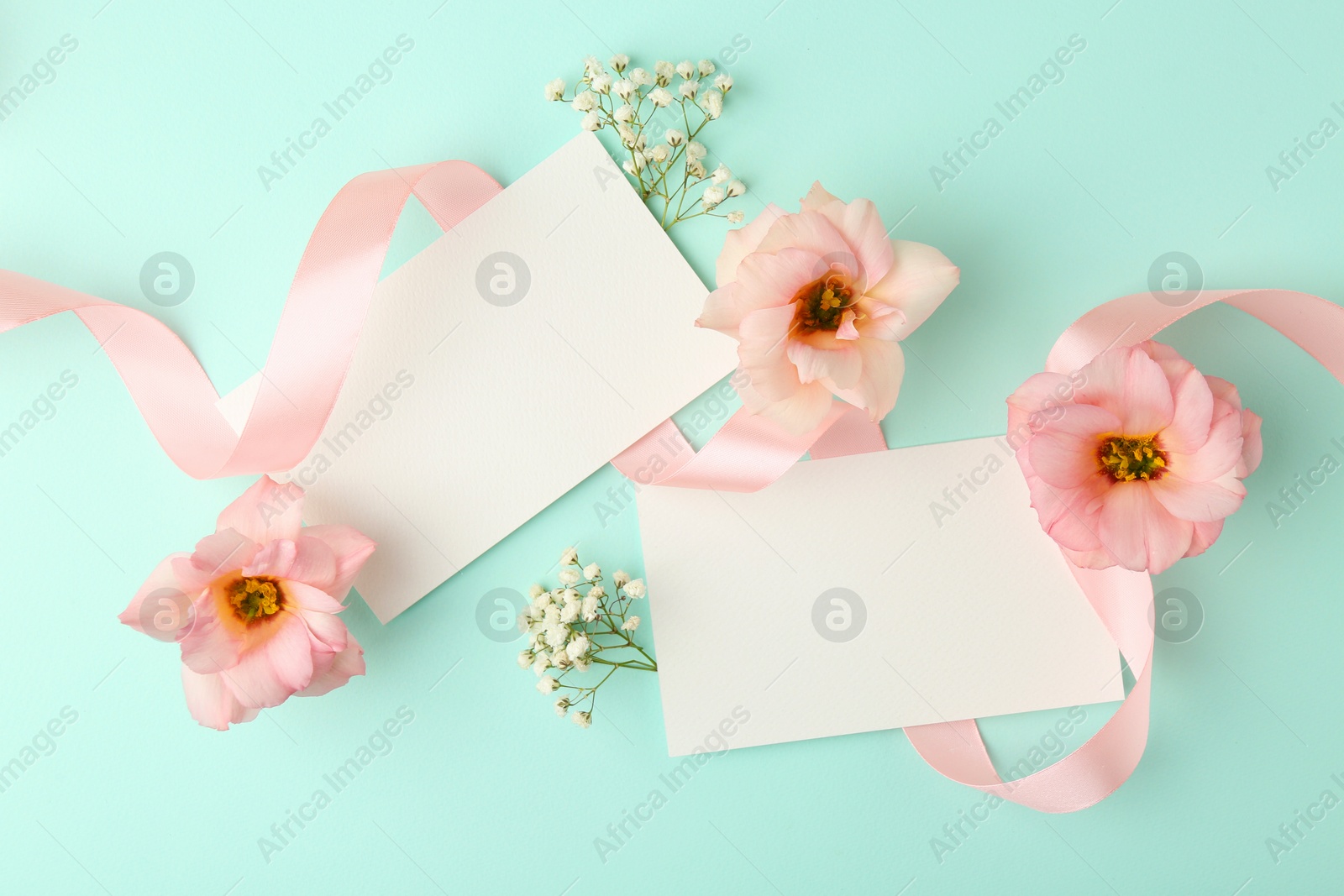 Photo of Floral composition with blank cards, flowers and ribbon on turquoise background, flat lay