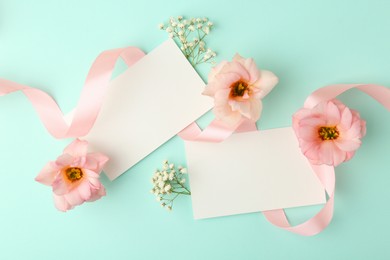 Photo of Floral composition with blank cards, flowers and ribbon on turquoise background, flat lay