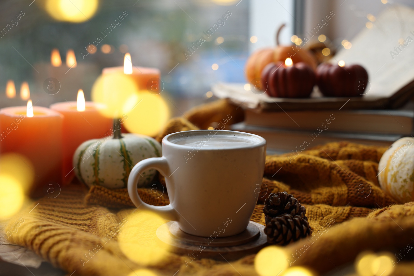 Photo of Cup of coffee, cones and soft sweater on table. Autumn atmosphere