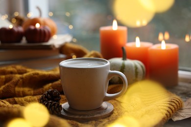 Photo of Cup of coffee, cones and soft sweater on table. Autumn atmosphere