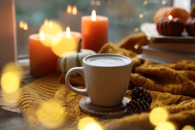 Photo of Cup of coffee, cones and soft sweater on table. Autumn atmosphere