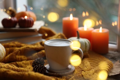 Photo of Cup of coffee, cones and soft sweater on table. Autumn atmosphere