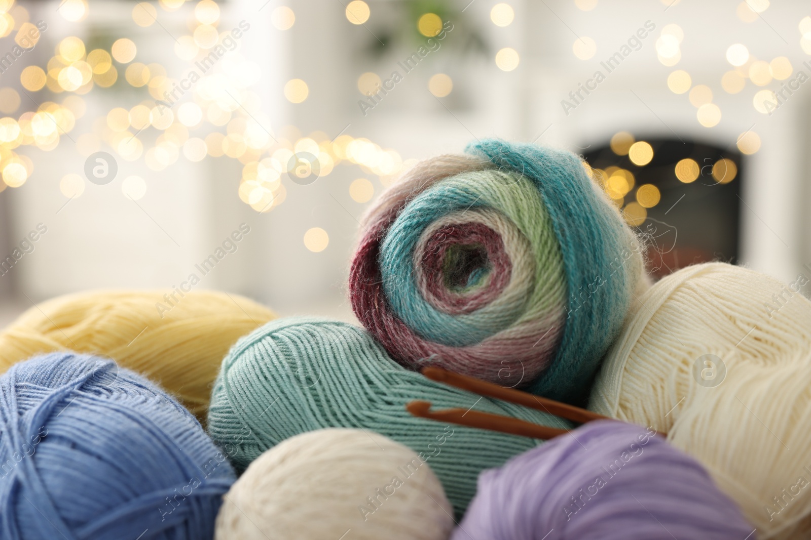 Photo of Colorful yarns and crochet hooks against blurred lights, closeup