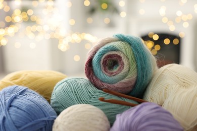 Colorful yarns and crochet hooks against blurred lights, closeup