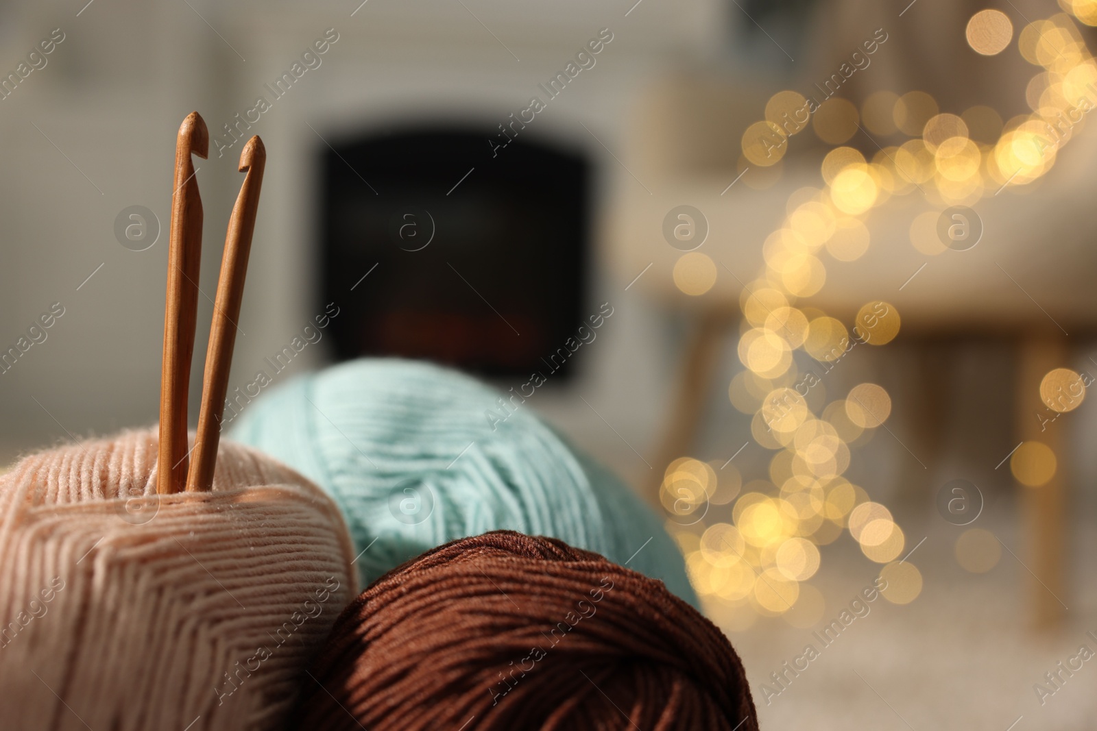 Photo of Colorful yarns and crochet hooks on blurred background, closeup. Space for text