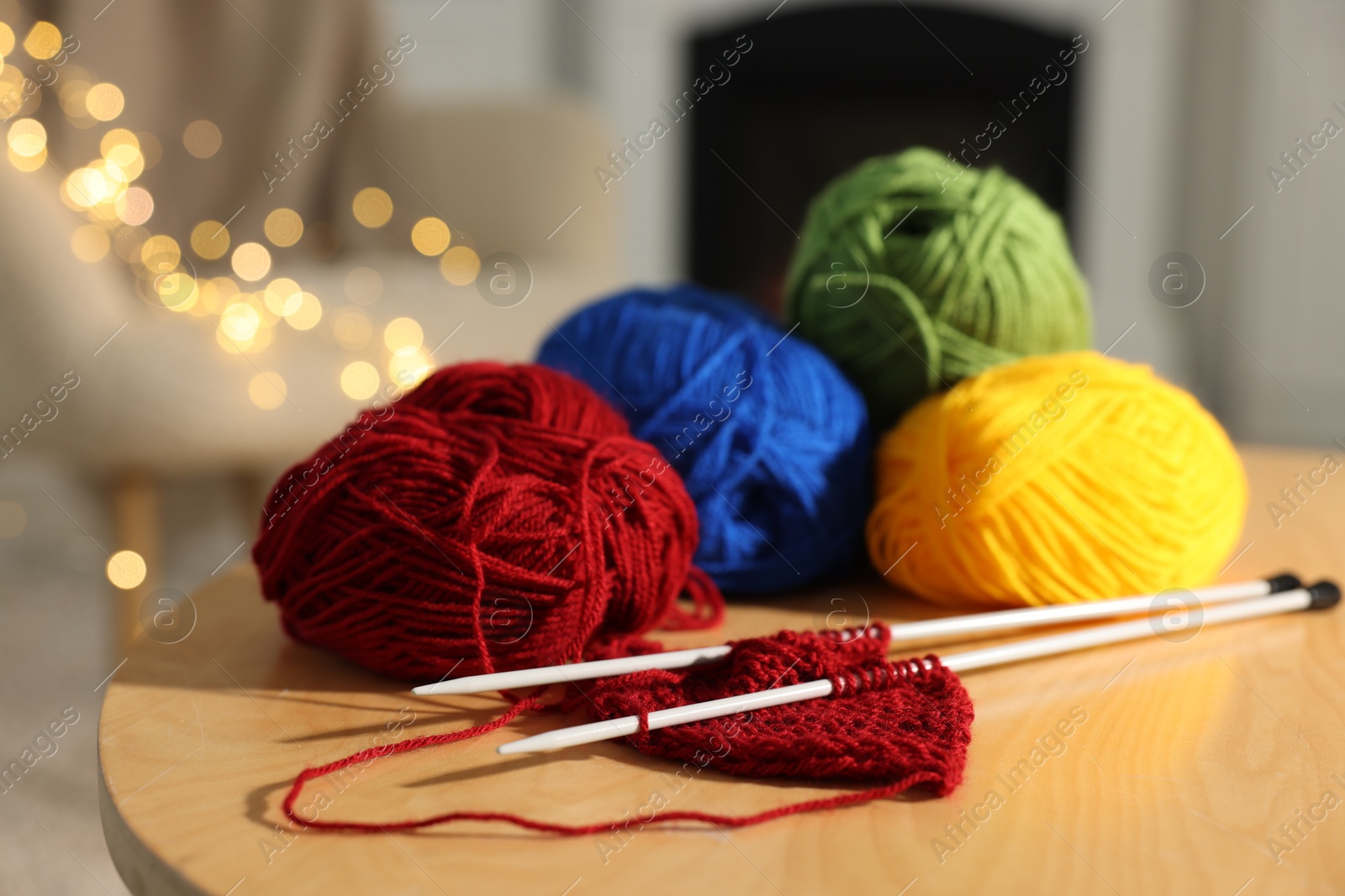 Photo of Colorful yarns, knitting needles and pattern sample on wooden table indoors, closeup