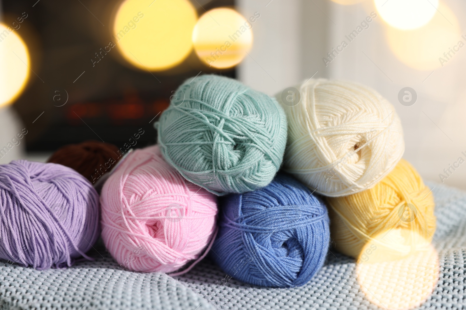 Photo of Many colorful yarns on blanket among blurred lights, closeup