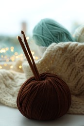 Yarn, crochet hooks and sweater on table indoors, closeup