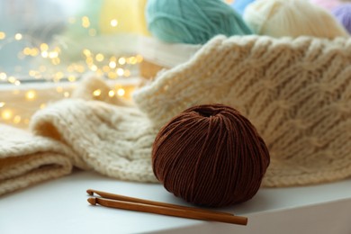 Photo of Yarn, crochet hooks and sweater on window sill, closeup