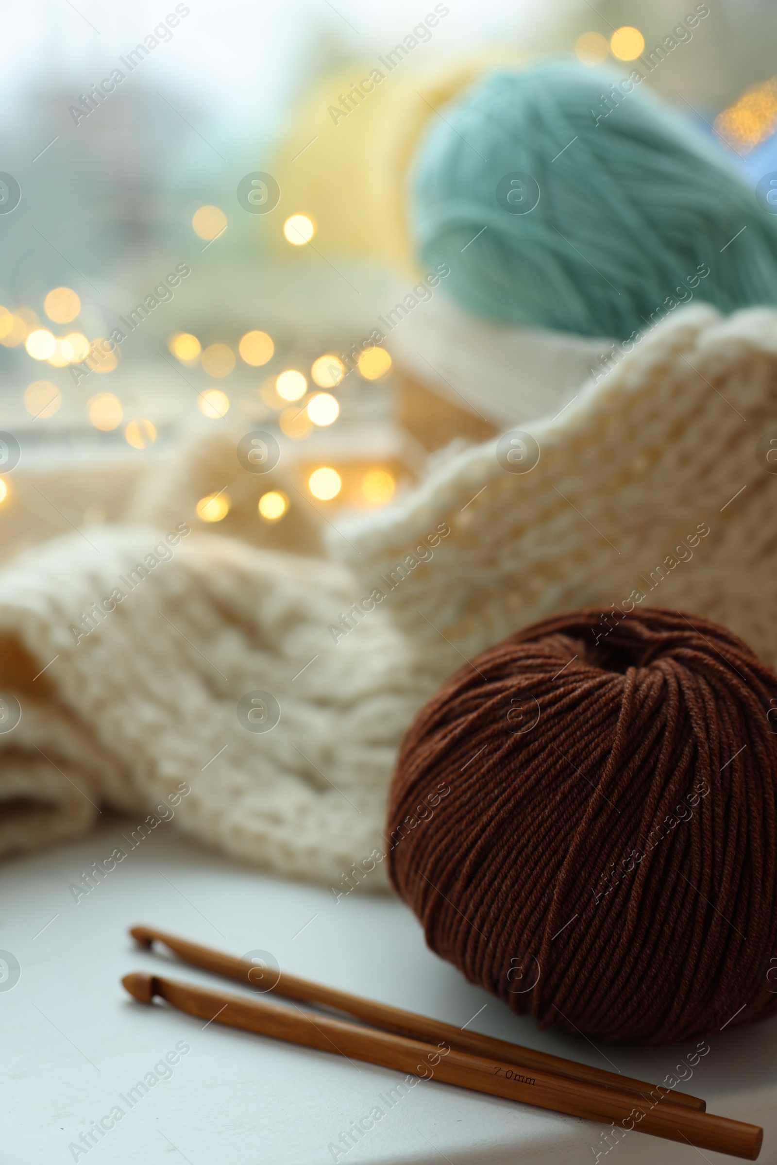 Photo of Yarn, crochet hooks and sweater on window sill, closeup