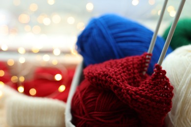 Photo of Colorful yarns, knitting needles and pattern sample on blurred background, closeup