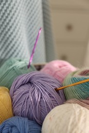 Photo of Many colorful yarns and crochet hooks on blurred background, closeup