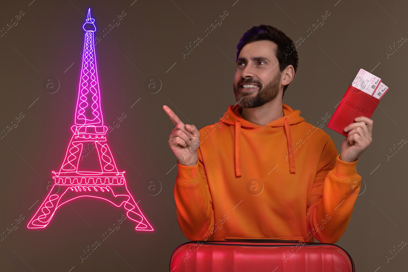 Image of Happy man with suitcase, passport and tickets pointing at neon illustration of Eiffel Tower on brown background