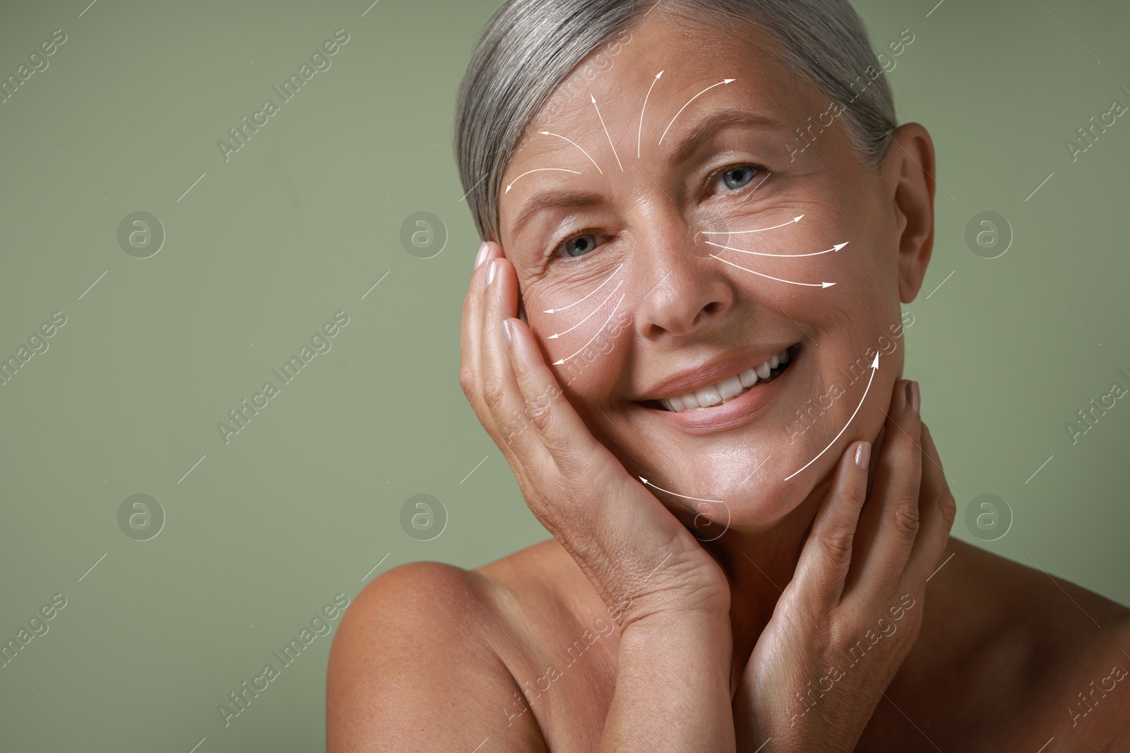 Image of Beautiful woman with healthy skin on sage green background. Arrows on face showing direction of massage moves