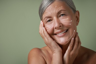 Beautiful woman with healthy skin on sage green background. Arrows on face showing direction of massage moves