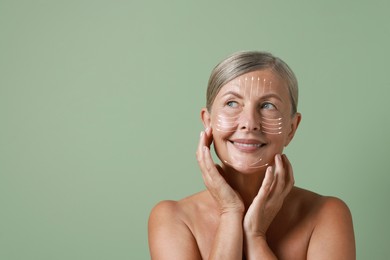 Image of Beautiful woman with healthy skin on sage green background. Arrows on face showing direction of massage moves