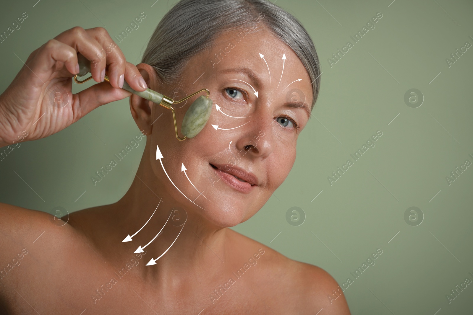 Image of Beautiful woman doing facial massage with roller on sage green background. Arrows on skin showing direction of moves