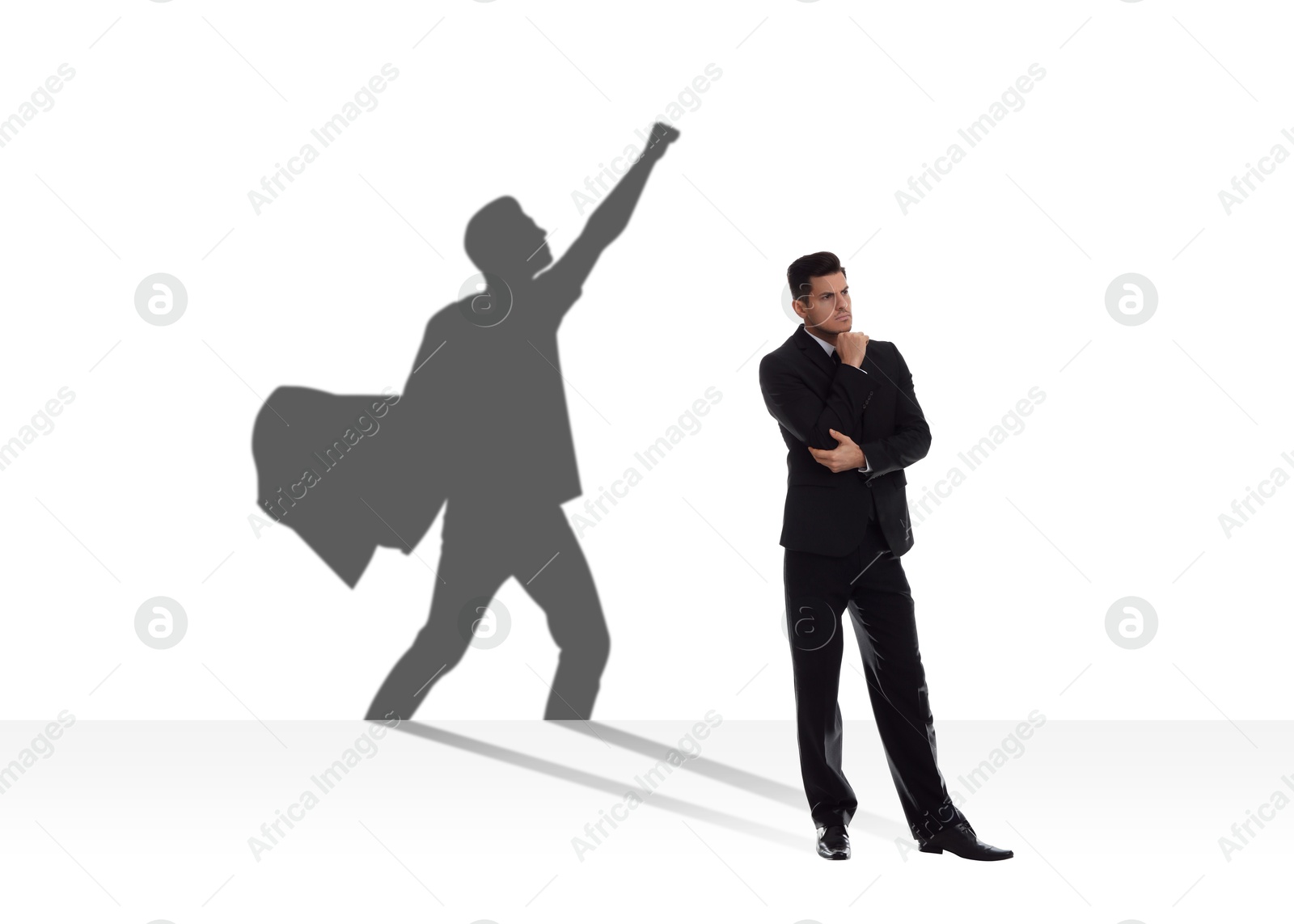 Image of Concentrated businessman casting shadow of superhero on white background. Success, confidence, power and determination concepts